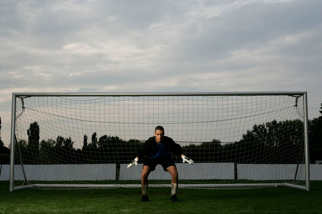 Crafting Captivating Headlines: Your awesome post title goes here Soccer goalie in action stance ready for defense in front of the net at dusk.